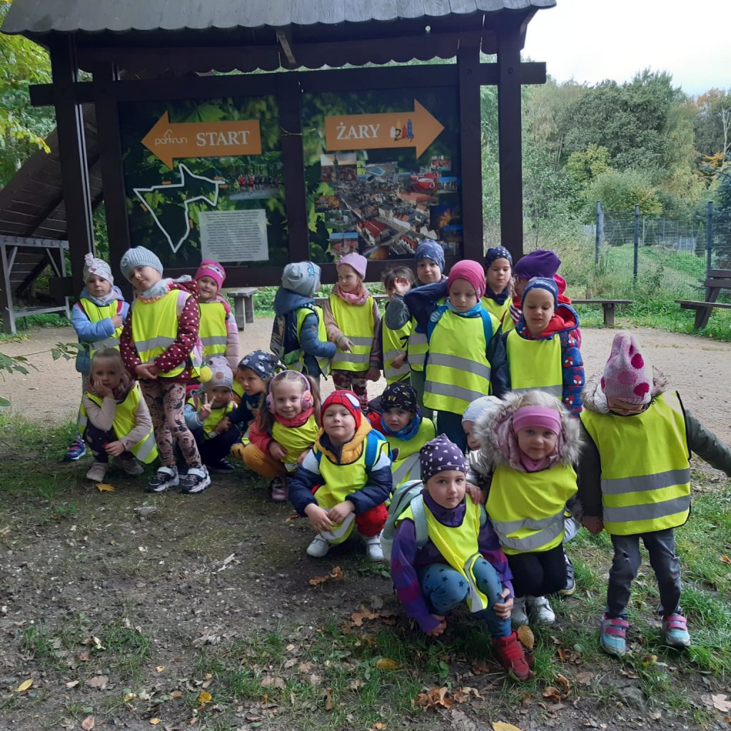 Dzieci stoją w lesie przy tablicy. 