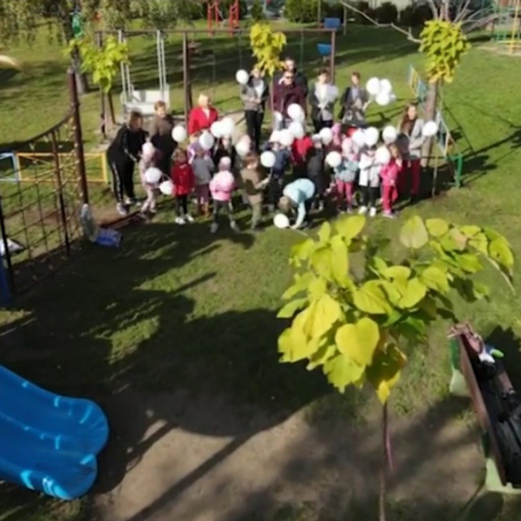 dzieci stoją na placu przedszkolnym z balonami
