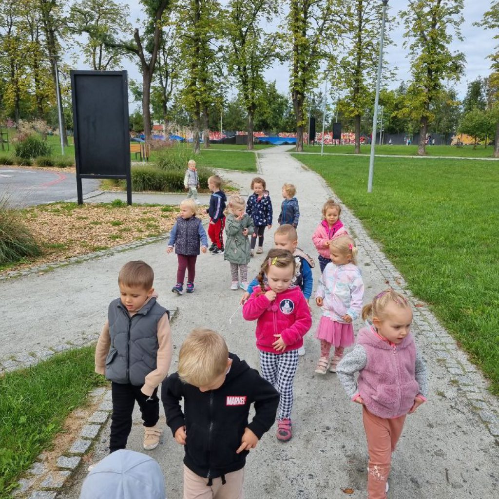 Grupa dzieci spaceruje po parku.