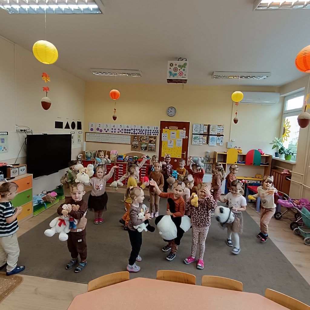 Przedszkolaki tańczą w rytm muzyki ze swoimi przytulankami.