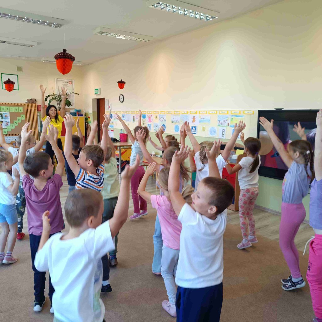 dzieci ćwiczą na dywanie z trenerem personalnym