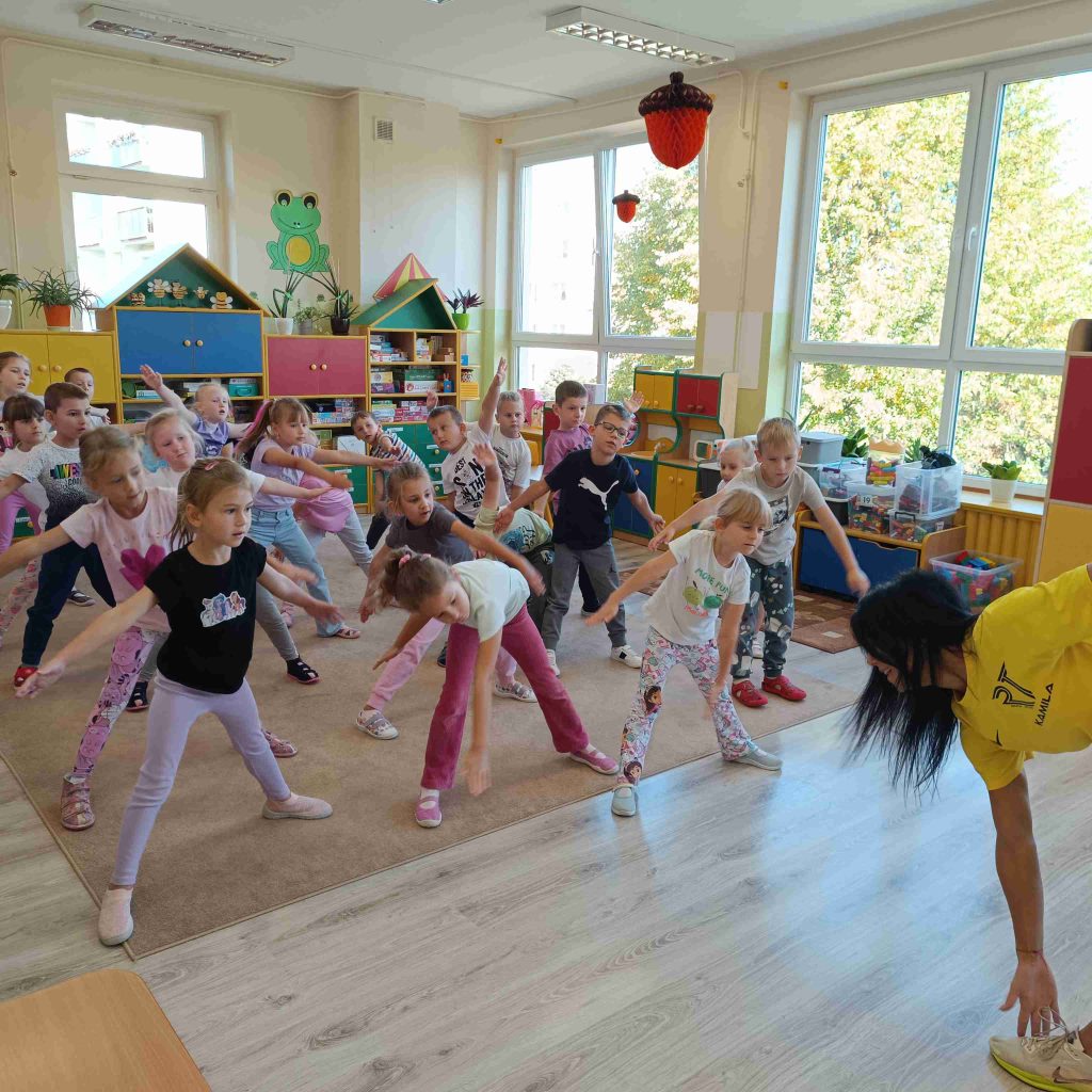 dzieci wykonują na dywanie ćwiczenia gimnastyczne
