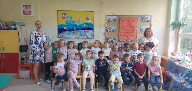 Grupa dzieci pozuje wraz z Paniami na tle tablicy