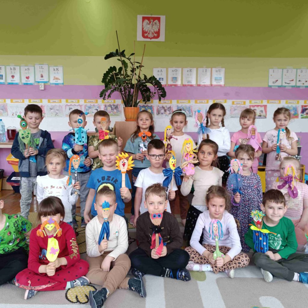 grupa dzieci pozy=uje z wykonanymi przez siebie kukiełkami