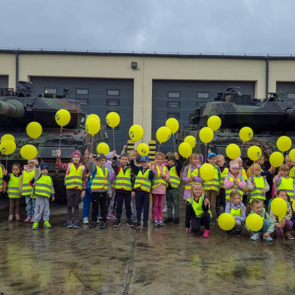dzieci trzymają balony na tle czołgów