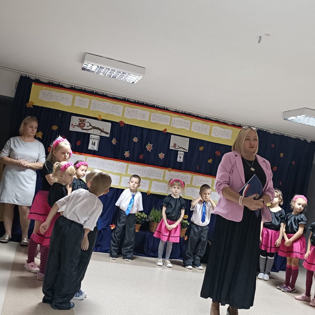 Pani Dyrektor stoi na tle dzieci ustawionych w podkowę
