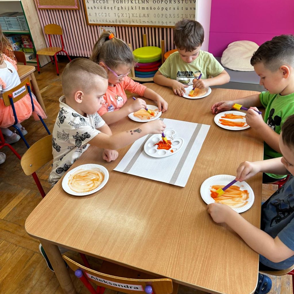 dzieci malują przy stolikach farbami