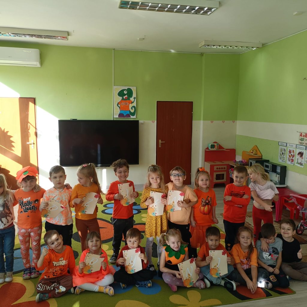 grupa dzieci ubranych na pomarańczowo pozuje z dyplomami