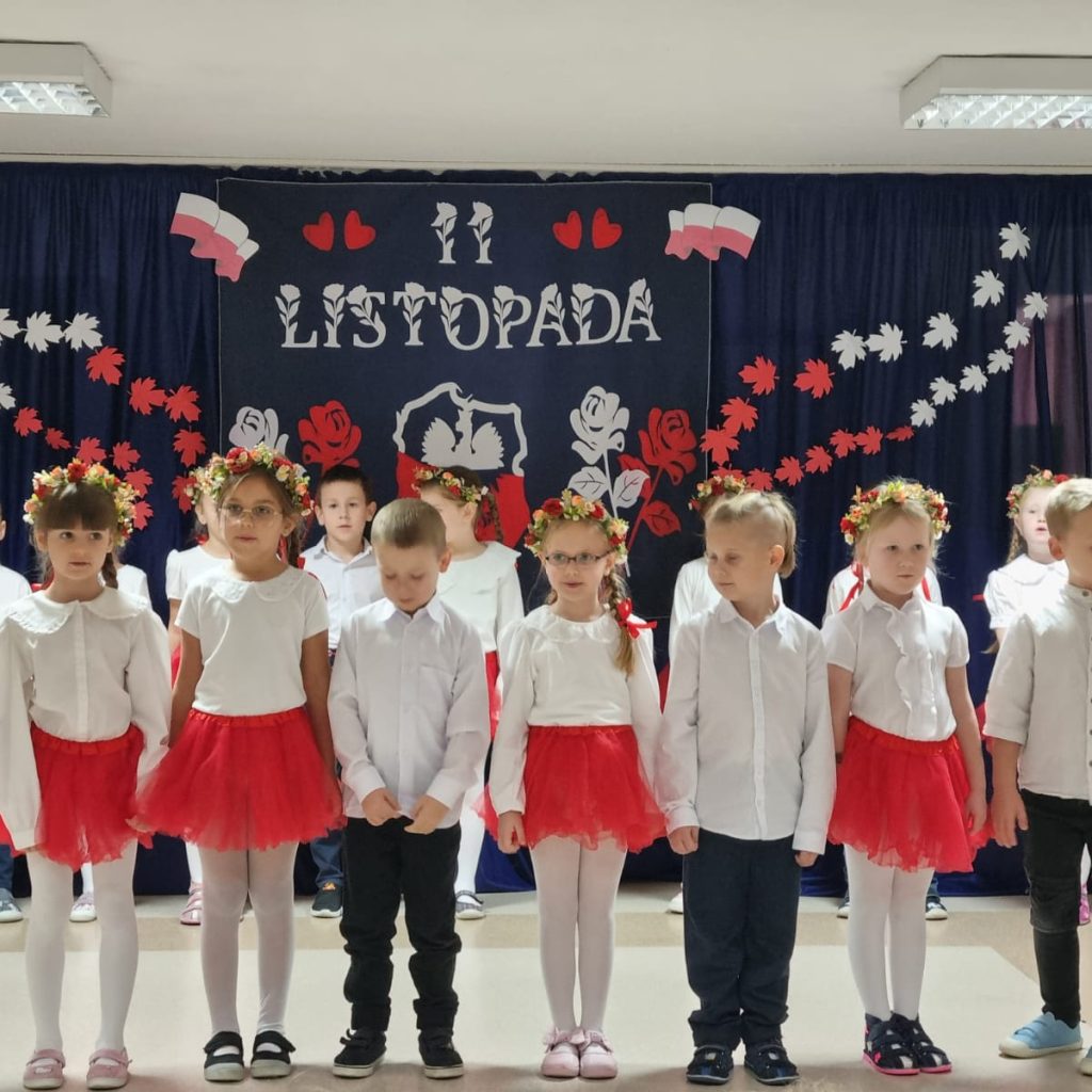 dzieci w biało czerwonych strojach recytują wiersz