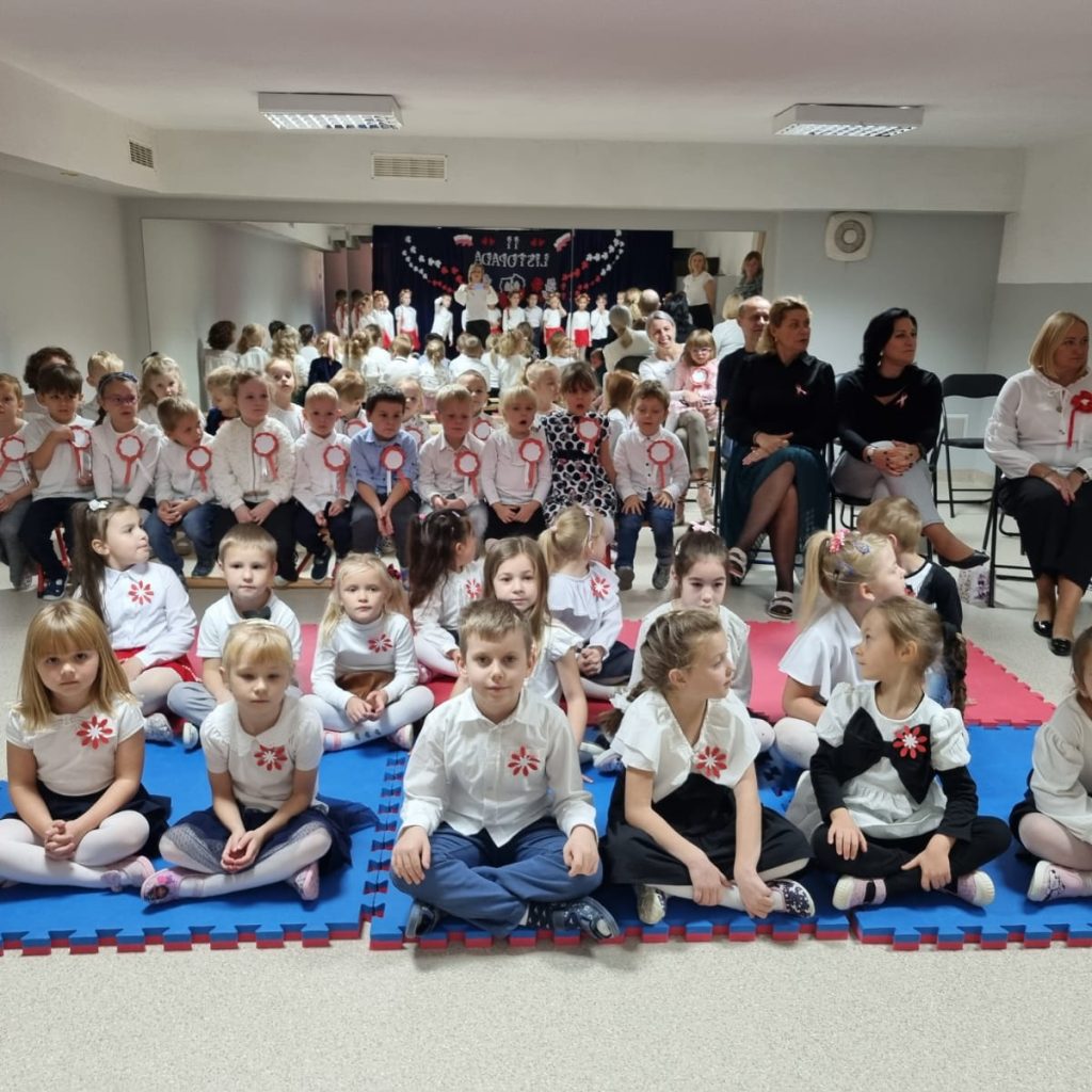 dzieci ubrane odświętnie pozują wraz z barwami narodowymi przypiętymi do ubrań