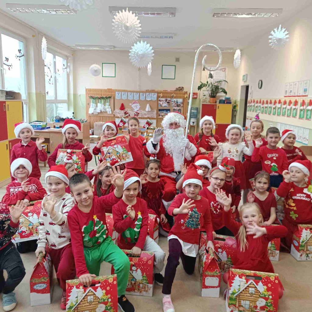 Grupa dzieci pozuje z Mikołajem i paczkami