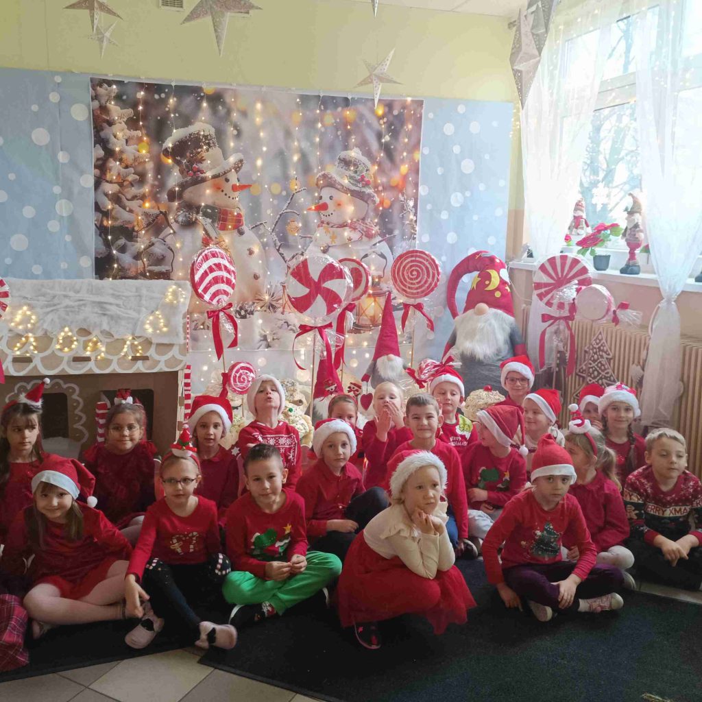 Grupa dzieci pozuje na tle świątecznych dekoracji