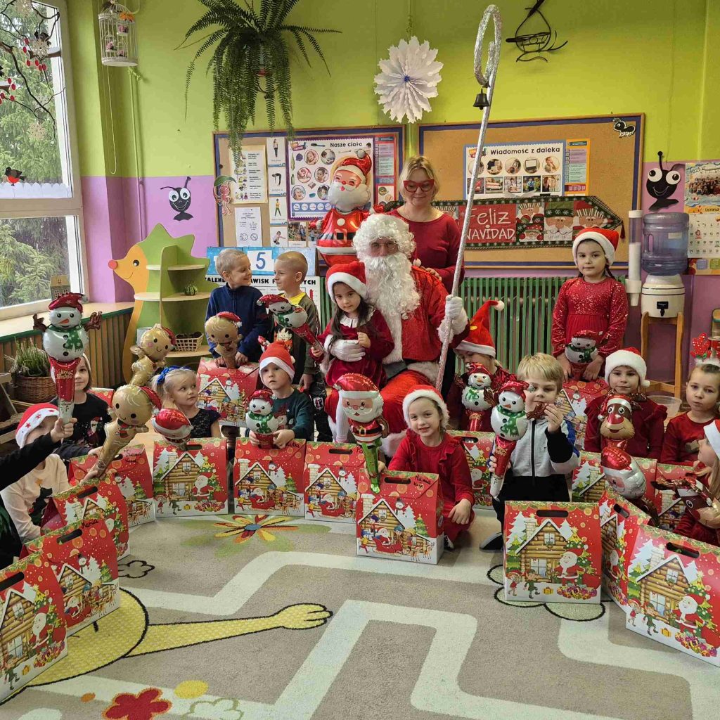 Grupa dzieci pozuje z Mikołajem, nauczycielką i paczkami