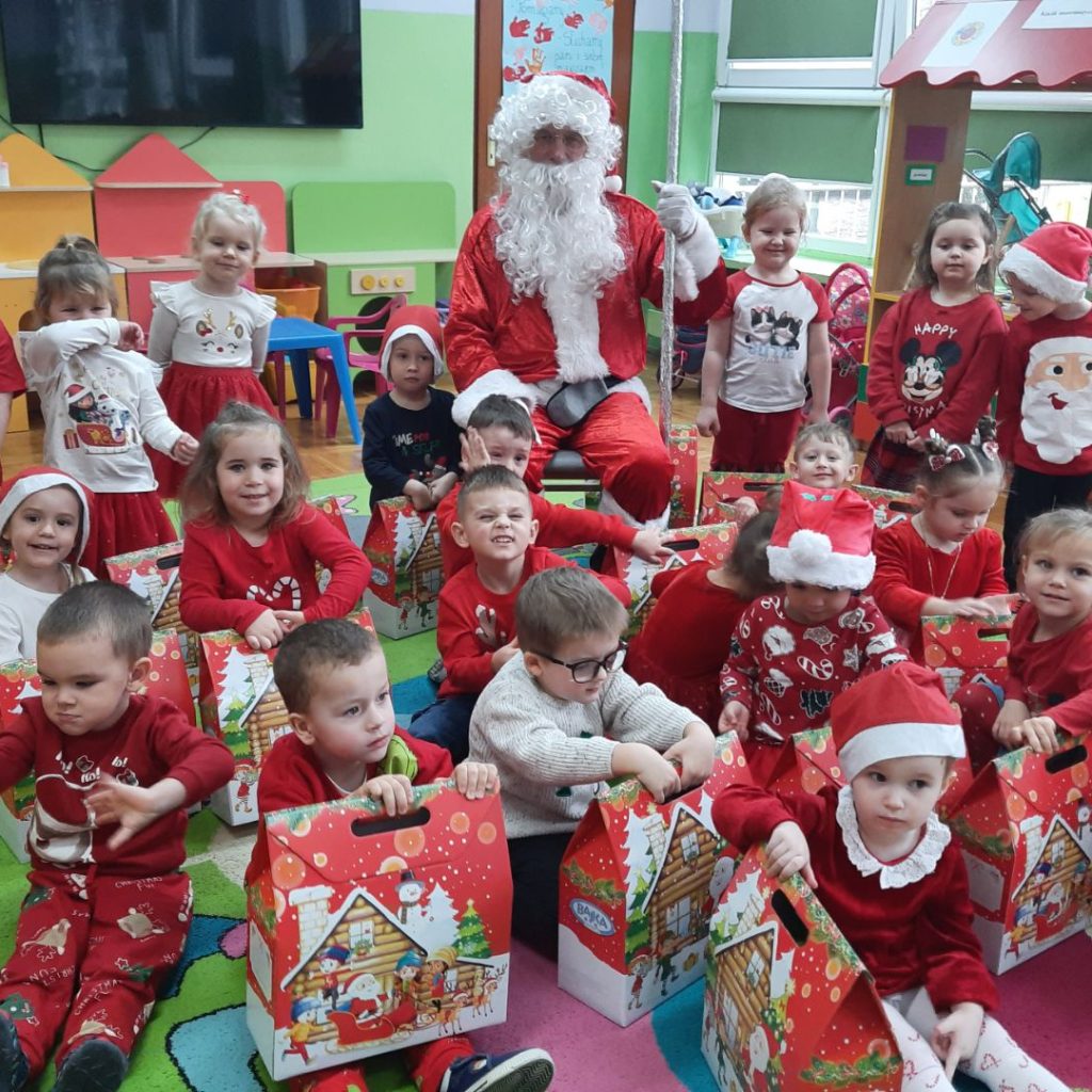 Grupa dzieci pozuje z Mikołajem i paczkami