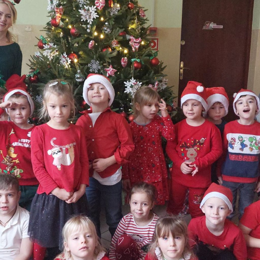 Grupa dzieci pozuje z nauczycielką i na tle choinki
