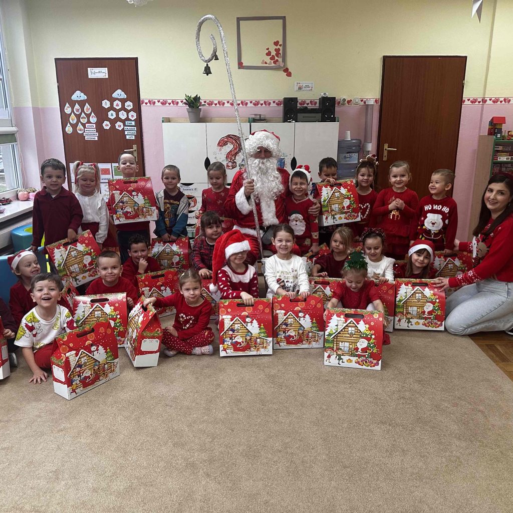 Grupa dzieci pozuje z Mikołajem, nauczycielką i paczkami