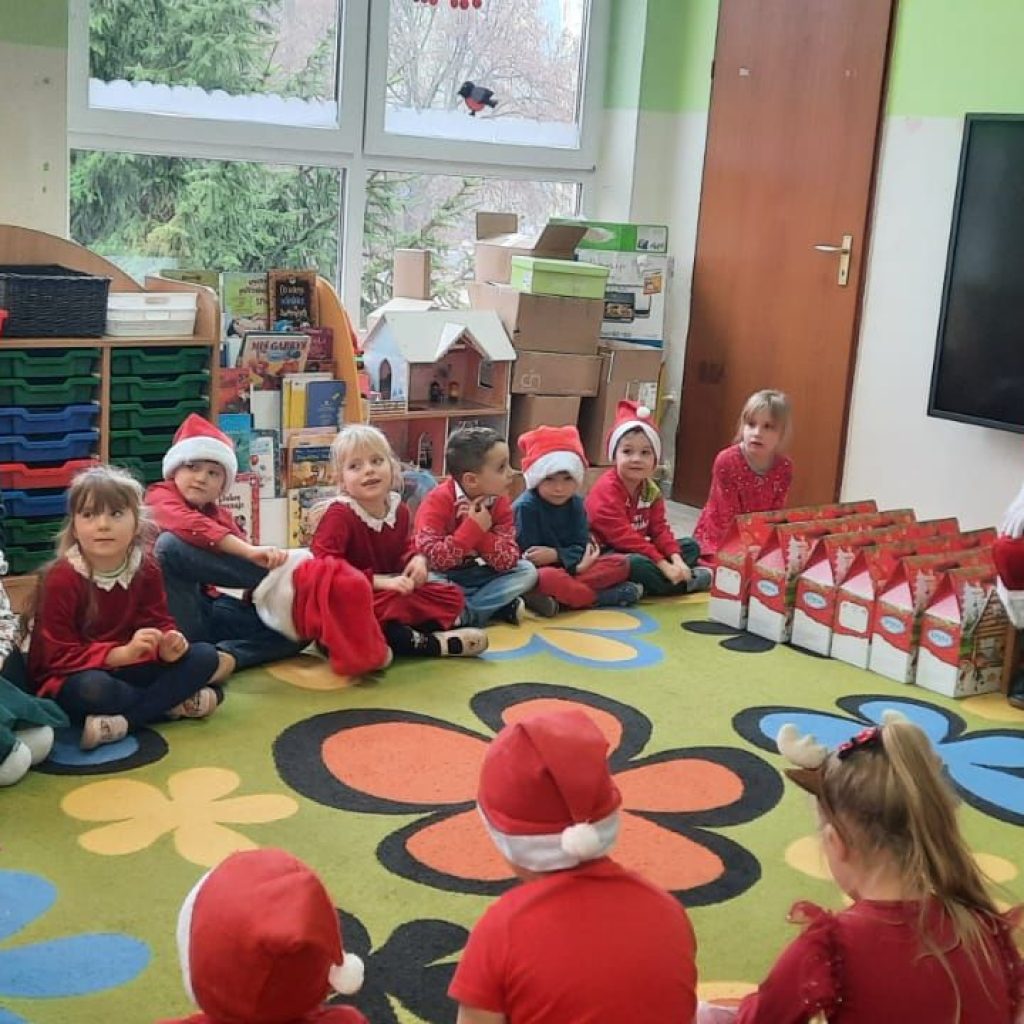 Grupa dzieci pozuje z Mikołajem, nauczycielką i paczkami