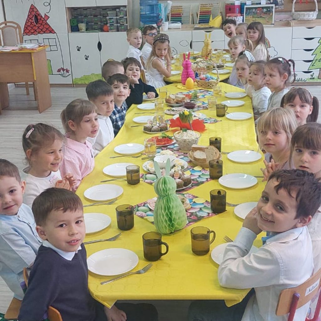 dzieci siedzą przy odświętnie ubranym stole