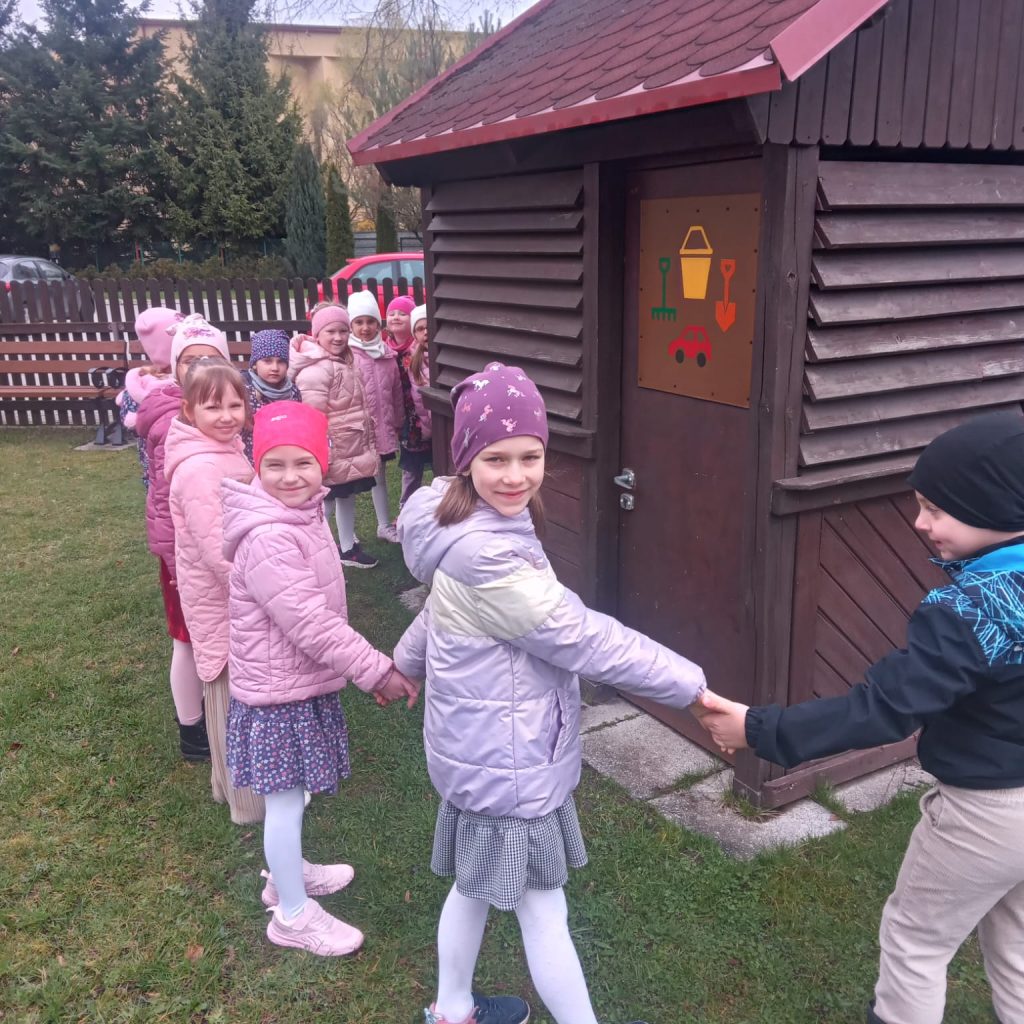 dzieci trzymają się za ręce dookoła szopy na zabawki ogrodowe