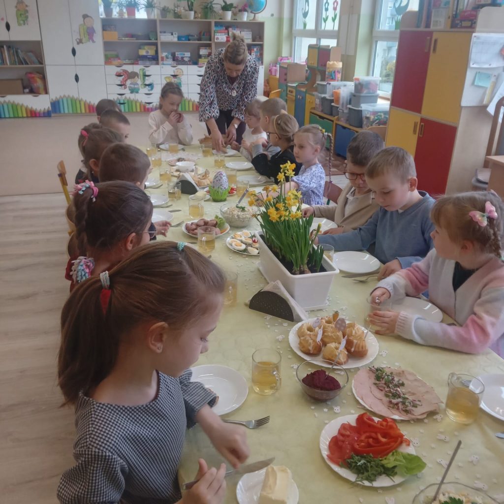 dzieci jedzą śniadanie przy odświętnie ubranym stole