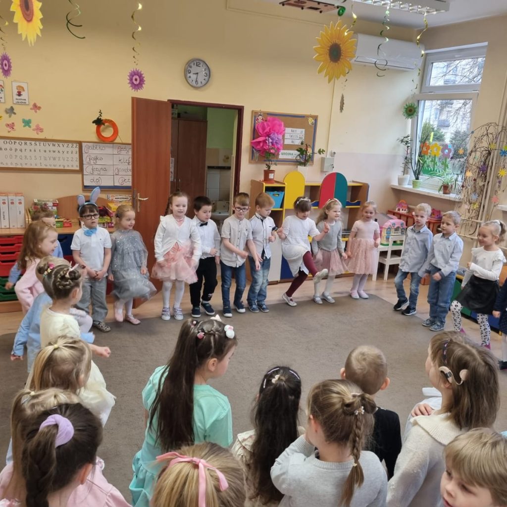 dzieci ustawione w kole na dywanie odświętnie ubrane