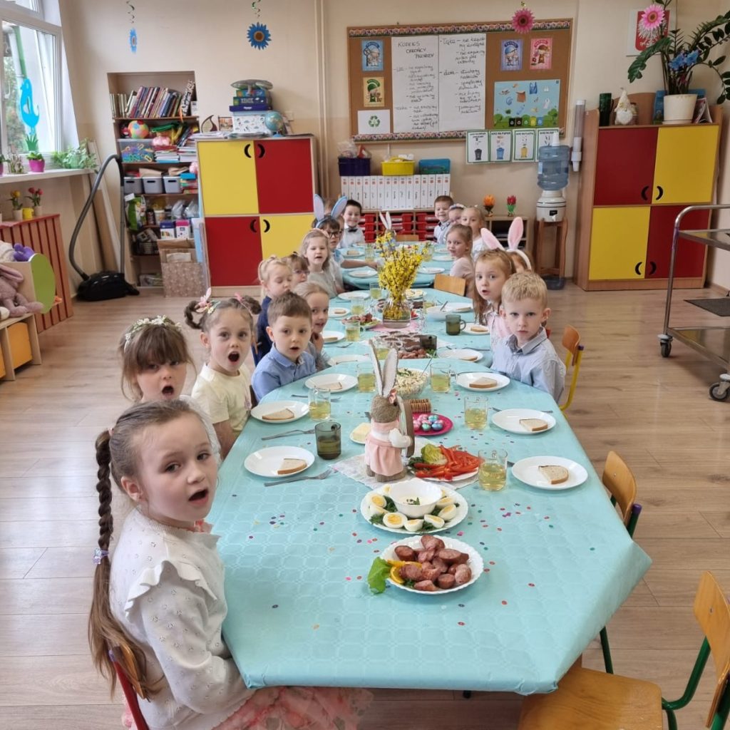 dzieci siedzą przy stole odświętnie ubranym