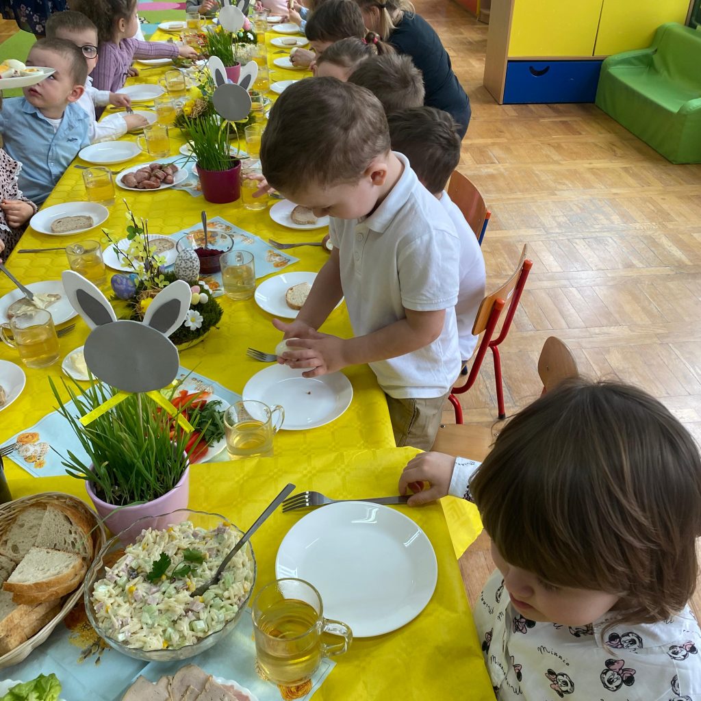 dzieci częstują się jedzeniem przy stole
